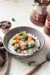 Rice porridge with banana, blueberries, chia seeds and honey sauce on a table, hot and healthy breakfast