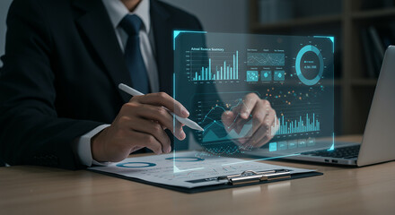 Fototapeta premium Businessman Analyzing Financial Data and Business Intelligence on a Holographic Display with Laptop and Documents in Office