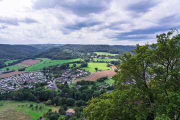 Nideggen, North Rhine-Westphalia, Germany, September 17 2023: Elevated view from the ruins of Burg Nideggen across the Eifel valley with village rooftops, fields and forested hills.