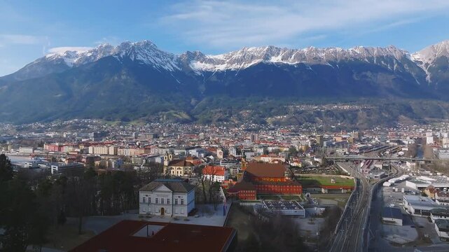 Aerial view of the Bergisel Ski Jump in Innsbruck, Austria, with gradual motion showcasing its modern design and the surrounding snow capped Alps.
