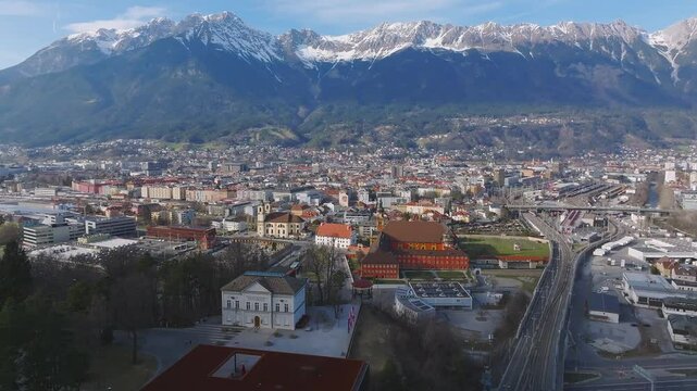 Aerial view of the Bergisel Ski Jump in Innsbruck, Austria, with gradual motion showcasing its modern design and the surrounding snow capped Alps.