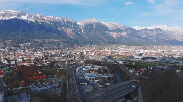 Aerial view of the Bergisel Ski Jump in Innsbruck, Austria, with gradual motion showcasing its modern design and the surrounding snow capped Alps.