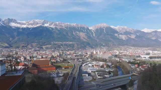 Aerial view of the Bergisel Ski Jump in Innsbruck, Austria, with gradual motion showcasing its modern design and the surrounding snow capped Alps.
