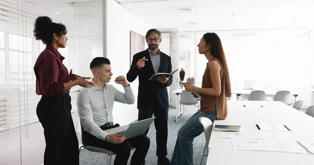 Multiethnic teammates discussing project updates gathered in modern conference room before or after negotiations, exchanging point of view, insights and creative solutions of business-related matters