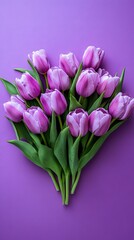 Obraz premium A creative display features lavender tulips arranged in a heart shape against a soft pink background