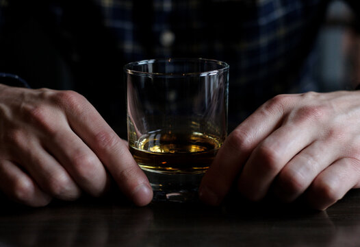 Close-up of a Man sitting at a bar with a glass of whisky