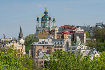 Obraz premium A vibrant cityscape showcases a blend of historical and modern architecture, with a prominent church featuring a blue-tiled dome reminiscent of Byzantine design Coexisting s - Kyiv, Ukraine 06-11-2024