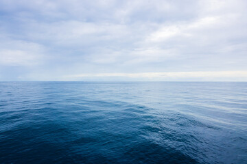 Photograph of vivid beautiful reflective ocean horizon with overcast cloudscape