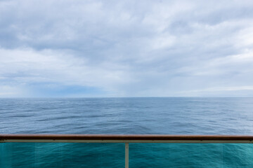 Image from the balcony of moving cruise ship looking out at the endless Atlantic ocean horizon bright beautiful cloudscape