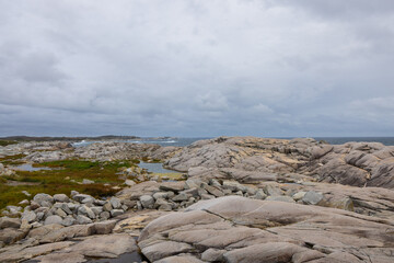 Moss covered granite stone shoreline view from Peggys Cove on a overcast rainy day in Nova Scotia...