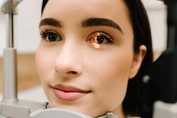 Ophthalmologist with slit lamp examines eyes and cornea of woman. Ophthalmologist illuminates eye...