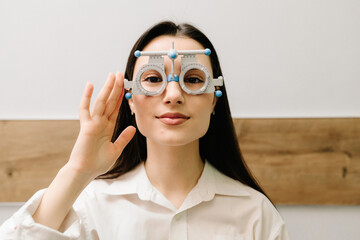 Girl in trial frame glasses on white background. Ophthalmologist examination for selection of trial...