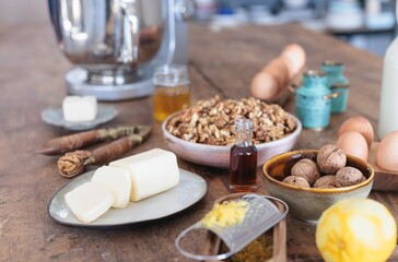 A cozy kitchen setting showcases ingredients for making homemade butter, including fresh dairy, eggs, nuts, and flavorings, creating a warm atmosphere for baking