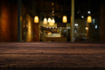 Beautiful dark brown tabletop and evening interior of a cafe or restaurant in the background