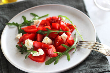Tomato salad with arugula and cheese in a plate on the table