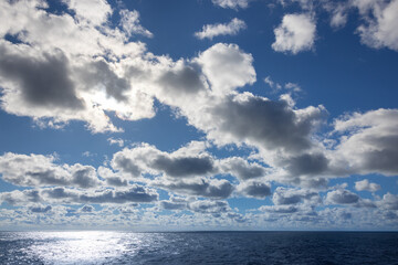 Obraz premium Beautiful open ocean on the horizon alluring bright sun lit cloudscape cumulus gray and white cloudy day.