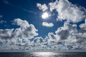 Bright sun flair blue sky and appealing cloudscape, Atlantic Ocean horizon.