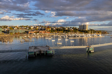 View from cruise ship looking towards sun rising on Portland Maine, USA port and sail boat marina cityscape on the horizon