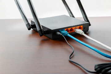 Modern wireless wifi router on wooden table with wires connected. Wireless connection concept,...