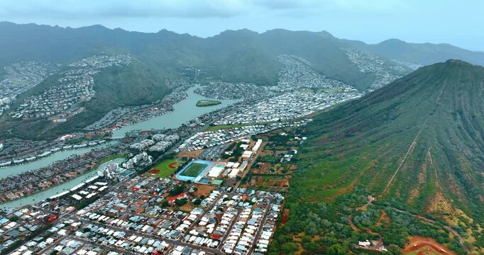 Dense rows of private houses scattered by the valley among the mountains and their slopes. Scenic view of Honolulu, Hawaii, USA. Aerial perspective.