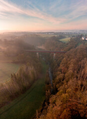 Naklejka premium Railway bridge crossing river in winter nature, drone shot at sunrise