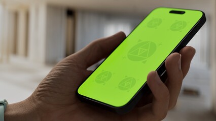 GREEN SCREEN CHROMA KEY A hand holding a smartphone with a green screen inside a renovated apartment