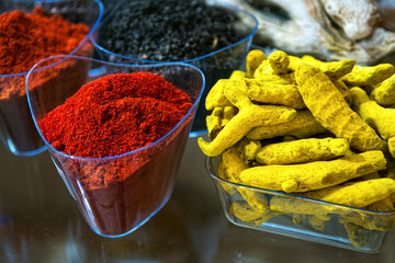 Indian spices. Ground red hot chili pepper and dry yellow turmeric roots in glass bowl.