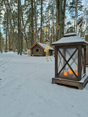 Tiny dwarf village hidden in the forest. Snow covered elf houses. Whimsical travel place. Old fashioned lantern.