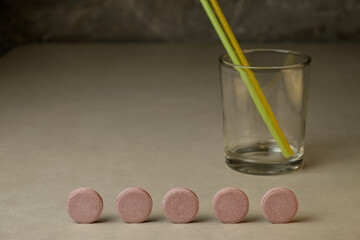 Colorful drink mixer tablets arranged in a line beside a glass and straws