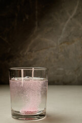 Sparkling pink effervescence in a glass glows against a smooth backdrop