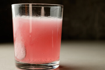 Refreshing pink beverage captured in a glass with ice during a cozy evening