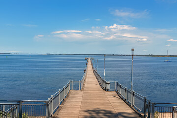 Fototapeta premium Wooden pier extending into calm sea under clear sky