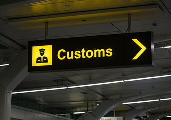 The bright yellow customs sign in an airport terminal guides travelers to the right direction for inspection.