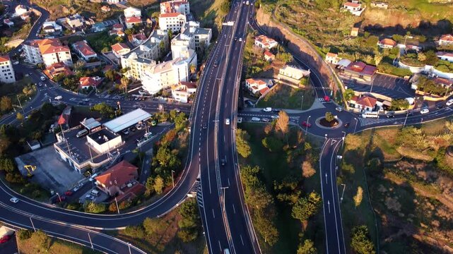 Aerial view of traffic in multiple roads through the coastal Canico de Baixo Town at the golden hour