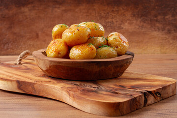 Baked new potatoes, with butter and dill, on a wooden plate, homely, rustic, no people,