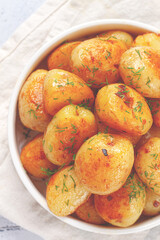 Baked new potatoes, with butter and dill, on a white plate, at home, no people,