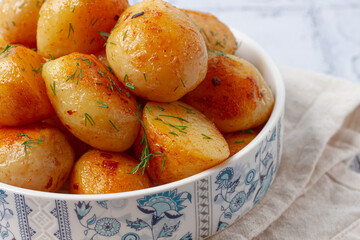 Baked new potatoes, with butter and dill, on a white plate, at home, no people,