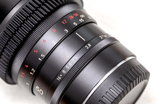 detailed close-up of camera lens showing the aperture and focus rings, highlighting the precision engineering, metallic texture, and manual control elements used in professional photography equipment