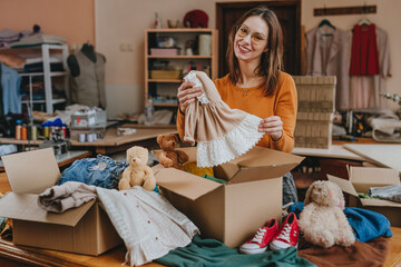Woman sorting an old out-of-use kid toy, clothes and shoes in box for charity or upcycling