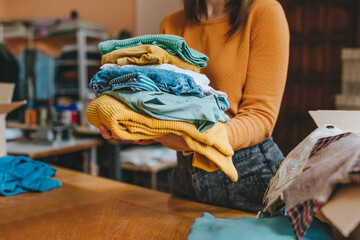 Close-up of female volunteer holding clothes collected for charity or converting discarded materials