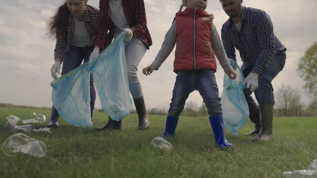 A small child with his parents collects trash in a park recreation area, group cleaning of the territory, ecology of cleanliness, collection of plastic bottles, waste, teamwork, happy family and kid.