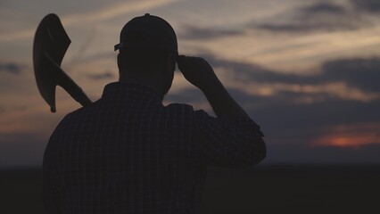silhouette of farmer with shovel field, agriculture, gardening business spring work, summer sunset on rural land, harvest time, man gardener goes dig land on plantation, work soil farm agronomist. © TO LOVE