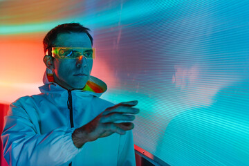 Man wearing glowing futuristic goggles looking at interactive screen