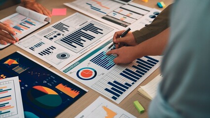 Professionals engage in a collaborative effort over various business charts and reports, focusing on data analysis and strategic planning in a modern office environment. SACTR