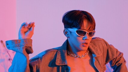 Close up of asian street dancer moving to pop music with neon light while diverse friend sitting...