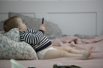 Toddler boy using phone on bed