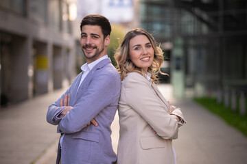 Man and woman in suit standing back to back outside