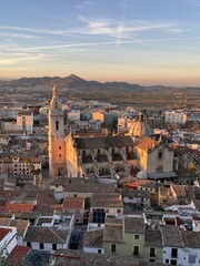 View of the Cathedral Basilica of Xativa, tiled roofs and mountains at sunset light in the suburbs of Valencia