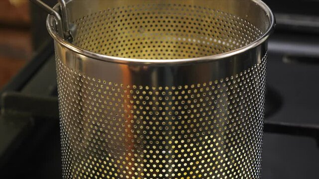 Deep fryer ladle with grid on burning stove. Medium shot.