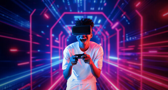 Teenager holding joystick and wearing VR goggles while enjoy playing games at neon abstract background. African man enjoy controlling controller and using augmented reality technology. Ingenuity.